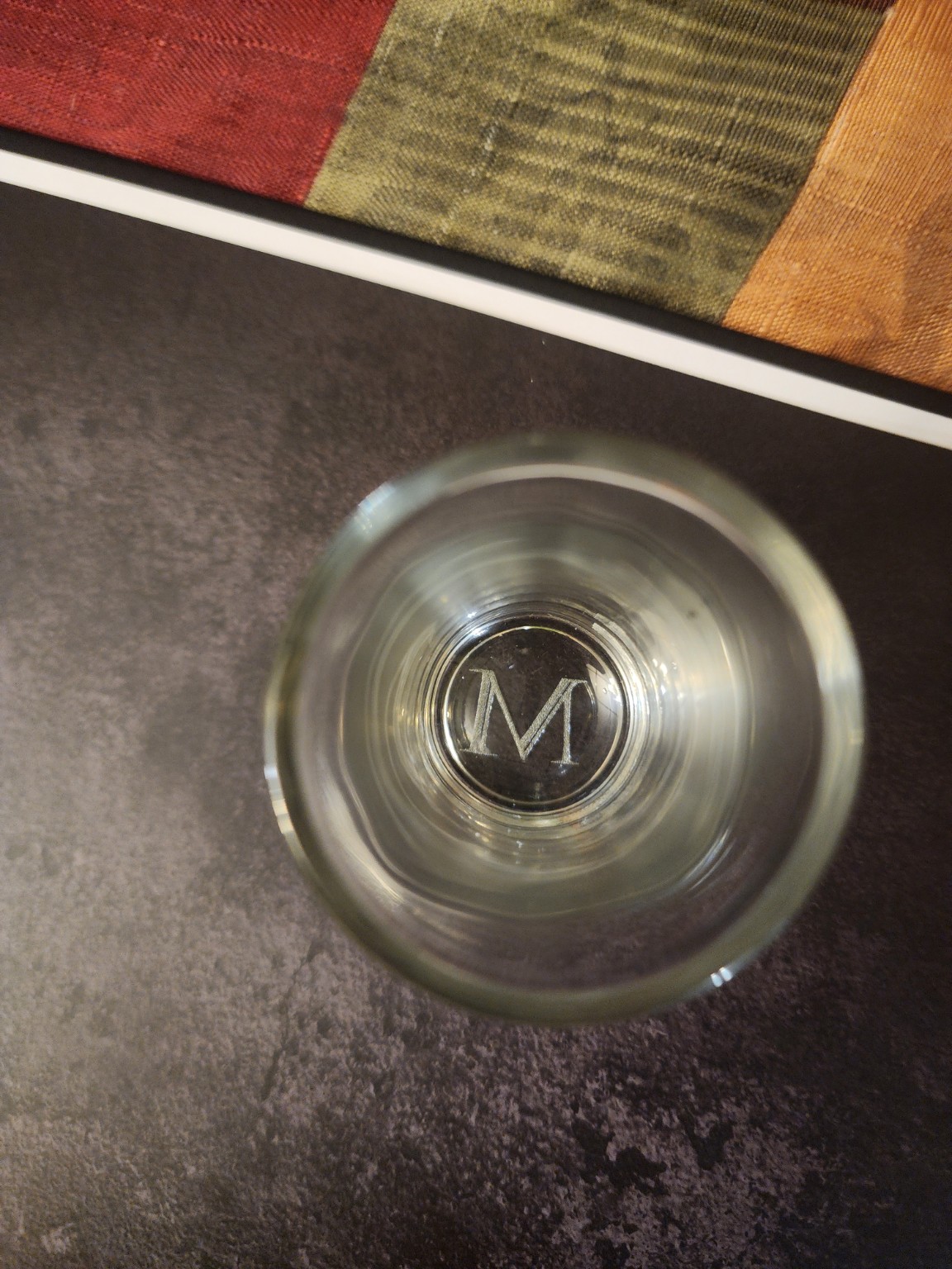 Looking down into an engraved glass — an M monogram cut beneath the base.